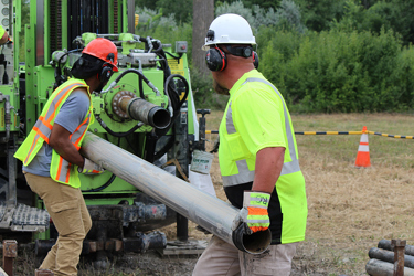 Two men prepare a sonic rig to gather continuous core samples.