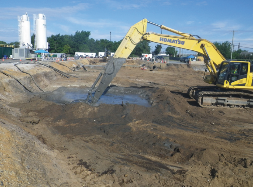An excavator mixing contaminants in a hole