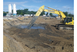 An excavator mixing contaminants in a hole