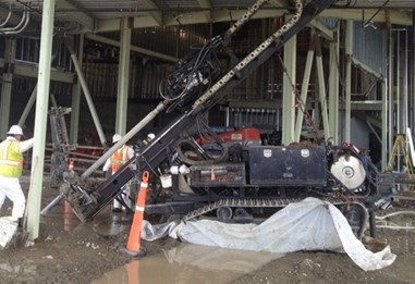 A sonic drill rig installing at an angle beneath a building