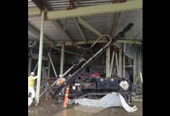 A sonic drill rig installing at an angle beneath a building